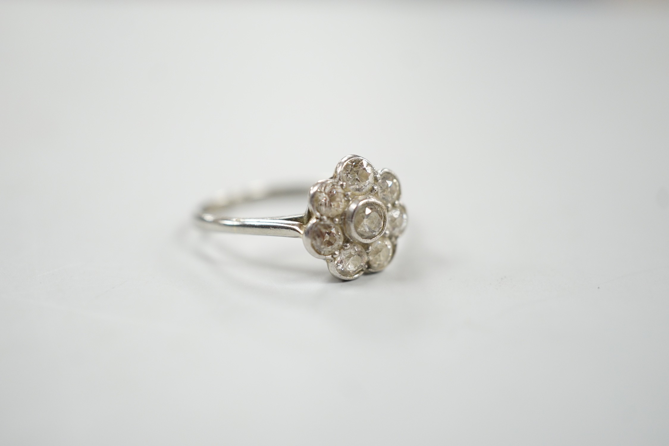 A 1920's 18ct, plat and millegrain set diamond flower head cluster ring, size O, gross weight 2.2 grams.